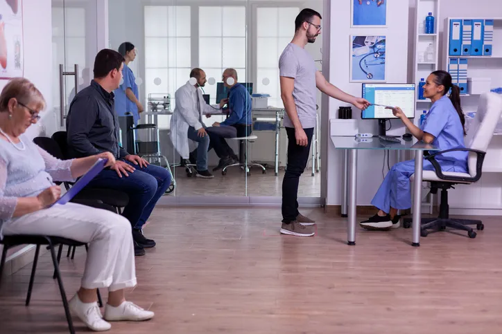 A hospital waiting area with people filling out forms for medical care.