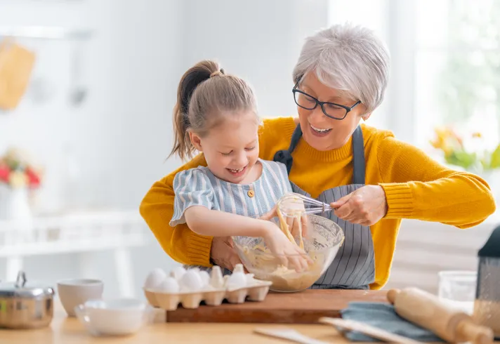 A grandmother and granddaughter baking together.