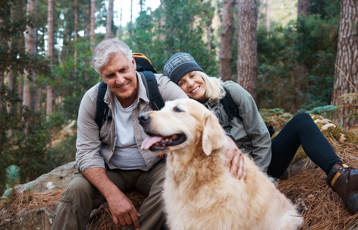 A retired couple hiking with their dog.