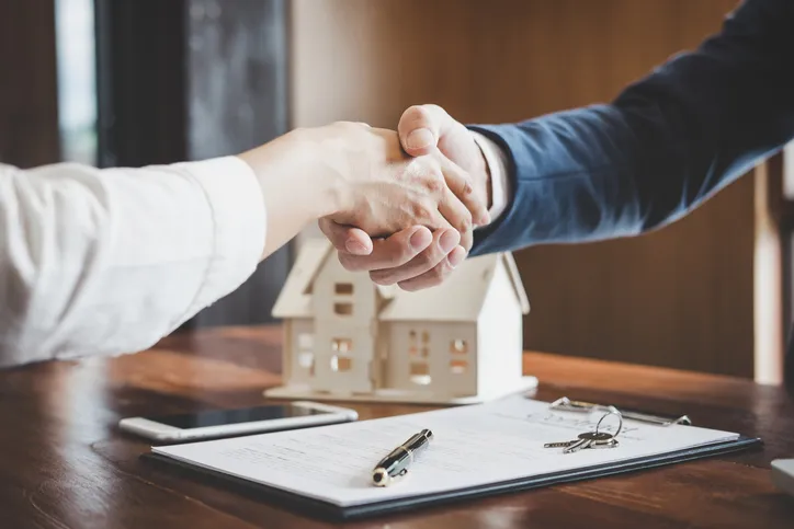 Real estate agent and client shaking hands.