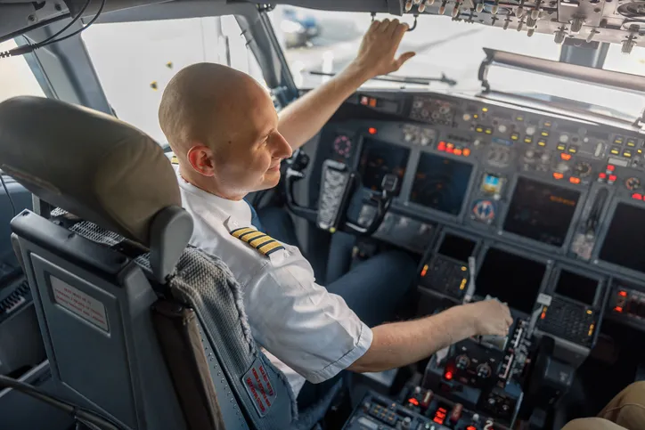 A professional pilot sitting in an airplane cabin, ready for takeoff.