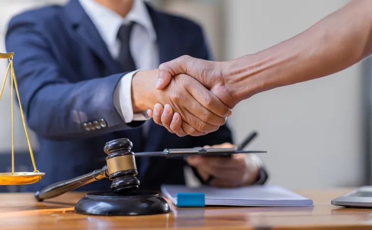 An estate planning attorney and client shaking hands over trust paperwork.