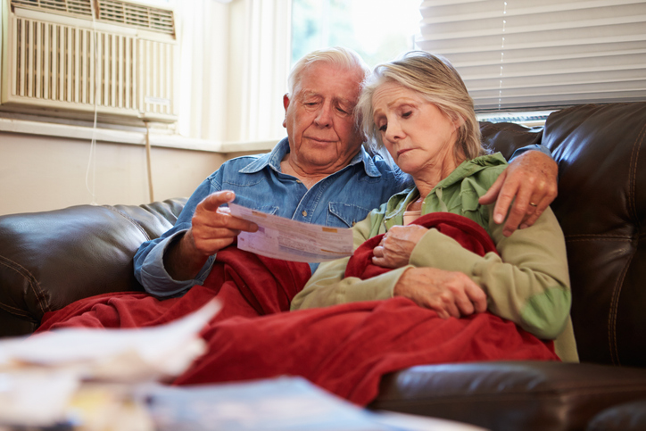 Worried senior couple on the couch, looking at documents.