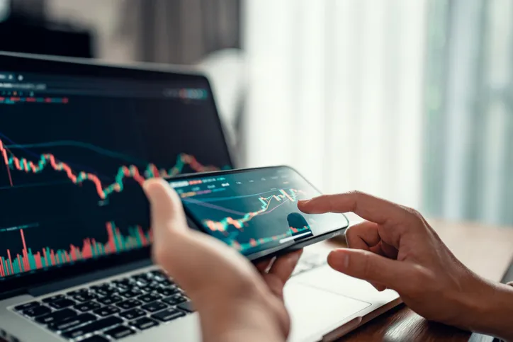 An investor on their smartphone and laptop.